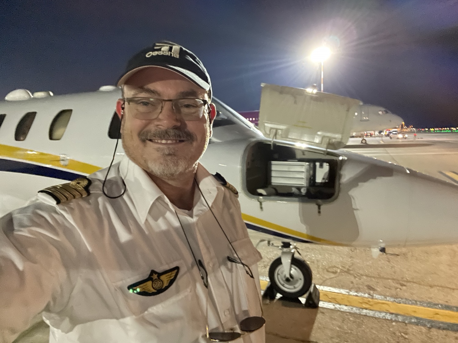 Nicolas en uniforme devant un avion d’affaires de nuit